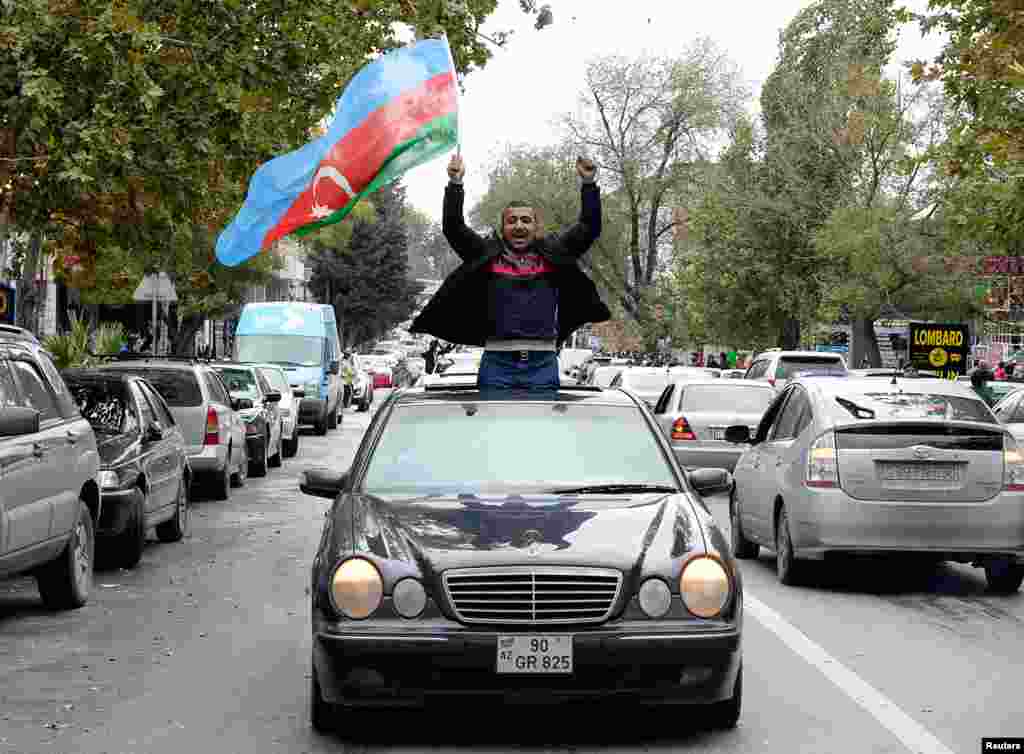 A man in Baku joins crowds celebrating in the Azerbaijani capital after President Ilham Aliyev claimed on November 8 that his forces had captured the city of Shushi/Susa. 