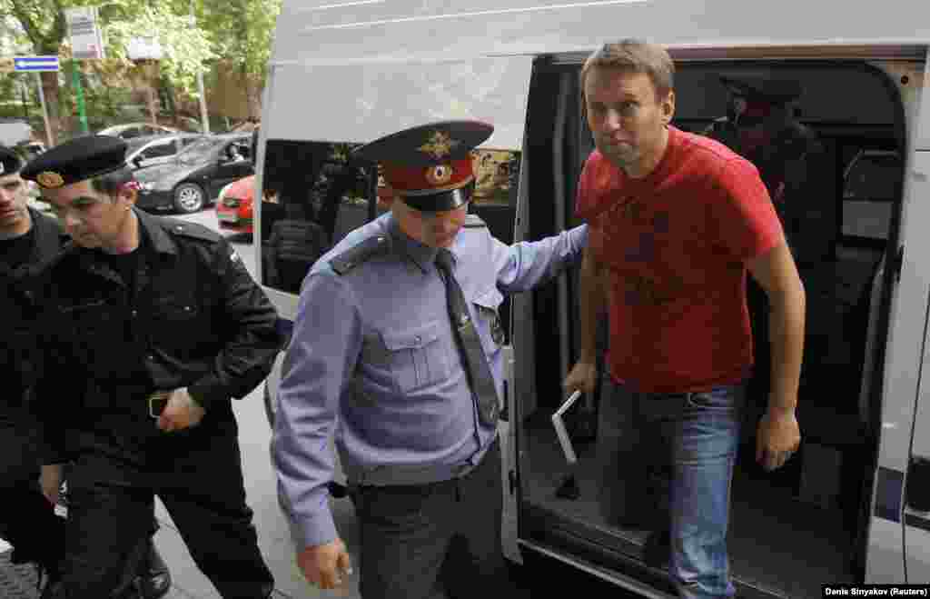 Служители на реда ескортират Навални до съд в Москва през 2012 г. Той е задържан на опозиционен митинг ден след встъпването в длъжност на Путин като президент. Полицията разчиства улиците от протестиращи и задържа хора, които носят бели панделки - символ на опозицията. &quot;Нашата стратегия е много проста: Само се разхождаме&quot;, казва Навални, преди да бъде отведен от полицията на 8 май сутринта. Той е осъден на 15 дни затвор за участие в неразрешено обществено събитие.