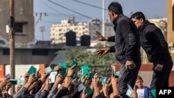 În imagine, palestinieni din Rafah, în sudul Fâșiei Gaza, își arată buletinele, pentru a primi rația de făină distribuită de Agenția ONU pentru refugiații palestinieni.