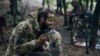 Un soldat ucrainean se joacă cu un câine în timp ce se odihnește pe teritoriul eliberat din regiunea Harkov. (AP Photo/Kostiantyn Liberov)