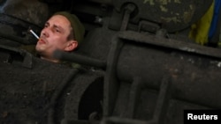Член на украински танков екипаж чака механиците да ремонтират танка му, след като се е върнал от мисия на фронтовата линия в Бахмут на 3 април.
