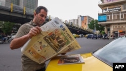 An Iranian man reads a newspaper on a Tehran street on April 12, with the front page focusing on the Iran-US nuclear talks in Oman.
