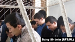 Ten ethnic Uzbek men await their sentencing inside a holding cage in the courtroom in Osh. Five of the men received life sentences for the brutal murders.