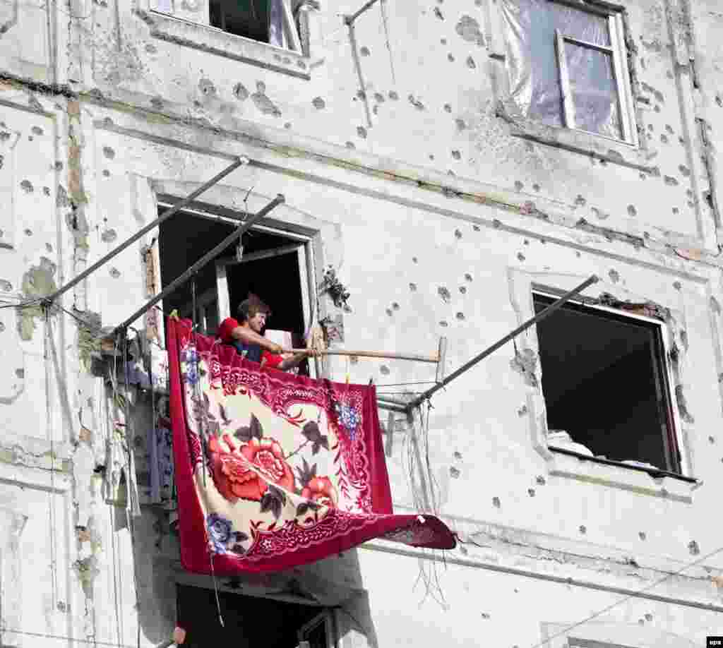 A woman hangs out a carpet as she returns to her destroyed home in Tskhinvali, the capital of South Ossetia, on August 23, a week after the end of the fighting.
