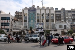 Oamenii încarcă obiecte jefuite de la ambasada iraniană în camioane în Damasc pe 8 decembrie.