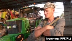 Боец 96-го батальона с позывным «Волк» рядом с поврежденной сельскохозяйственной техникой