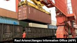 A worker in Lianyungang in China's Jiangsu Province climbs out of a freight train bound for Kazakhstan as a container is loaded onto the vehicle. (file photo)