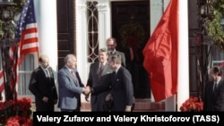 Secretarul general al Comitetului Central al Partidului Comunist al URSS, Mihail Gorbaciov (al doilea din stânga), strânge mâna vicepreședintelui SUA de la acea vreme, George Bush, în prezența președintelui american Ronald Reagan.