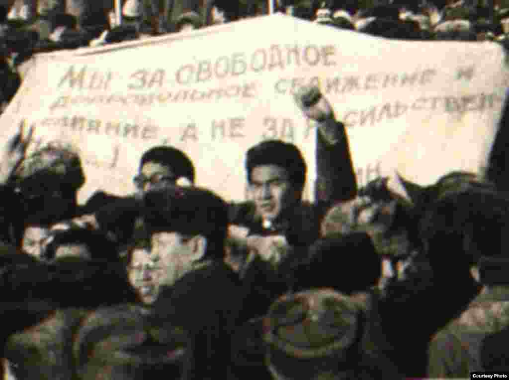 Алматыдагы каршылык акциясына чыккандар "Биз эркин жана ыктыярдуу биригүүнү жактайбыз" деген ураан көтөрүп турушат. - Участники демонстрации на площади Брежнева, ныне площадь Республики, держат плакат с надписью «Мы за свободное добровольное слияние и сближение...». Алматы, декабрь 1986 года. Фотокопия из Центрального государственного архива Алматы.