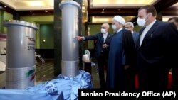 Iranian President Hassan Rohani (center) listens to Atomic Energy Organization head Ali Akbar Saleh (left) while visiting an exhibition of Iran's new nuclear achievements in Tehran.