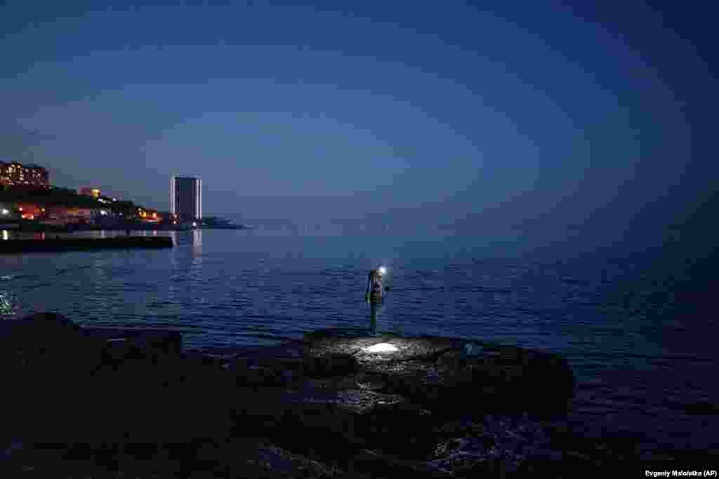 A man fishes on a breakwater at the Arcadia beach in the Ukrainian port city of Odesa.