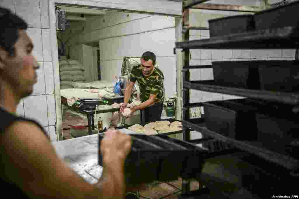Workers prepare dough for the oven. 
