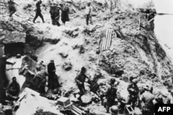 Soldați americani din Batalionul 2 Ranger înconjoară prizonieri germani, la 6 iunie 1944, pe Pointe du Hoc, situat pe o stâncă ce domină plaja Omaha Beach, după ce forțele aliate au luat cu asalt plajele din Normandia în timpul Zilei Z.