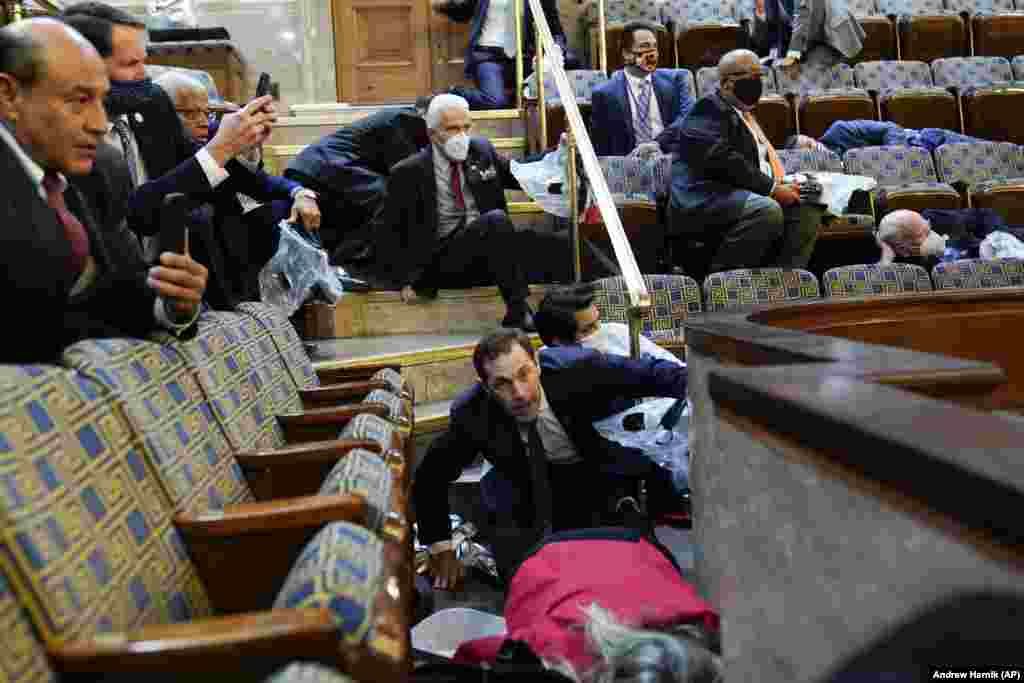 Un grup de congresmeni americani adăpostindu-se în Camera Reprezentanților, 6 ianuarie 2021.