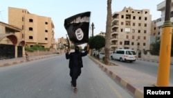 Un membru al militanților Statului Islamic flutură un steag în orașul sirian Raqqa.