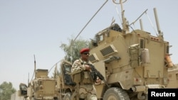 An Iraqi soldier patrols near U.S. military armoured vehicles as the U.S. Army prepares to leave a military base in Mahmudiyah in July.