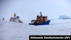 Un spărgător de gheață taie calea unei nave de marfă în apropierea unui port de pe insula Alexandra Land, lângă Nagurskoye, cel mai nordic avanpost militar al Rusiei.