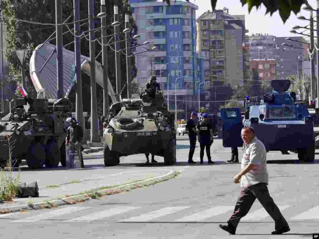 Čovek prolazi ispred vojnika KFOR-a i pripadnika EU policije koji čuvaju glavni most u Mitrovici koji deli grad na severni i južni deo, 28. jul 2011.