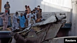 ځايي خلک د نسکورې شوې الوتکې د ملبې سره ولاړ دي.