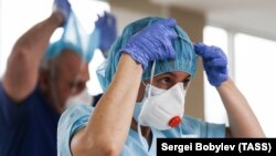 Беткап кийип жаткан медицина кызматкери.