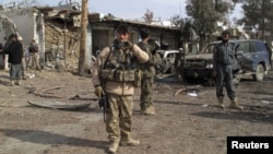 Security forces keep watch at the scene of a suicide bombing in Helmand Province