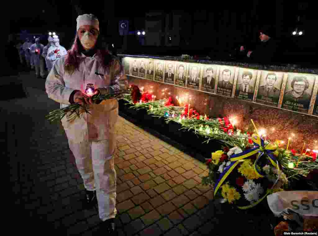 Staff from the Chernobyl nuclear plant hold candles as they visit a memorial dedicated to firefighters and workers who died after the disaster, during an overnight service in Slavutych. 