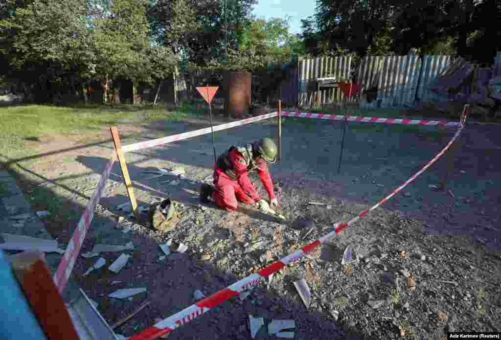 A sapper in protective gear works on an unexploded shell next to a house in the Azerbaijani village of Agdam on July 15. Several villages on both sides of the Armenian-Azerbaijani border have been shelled.