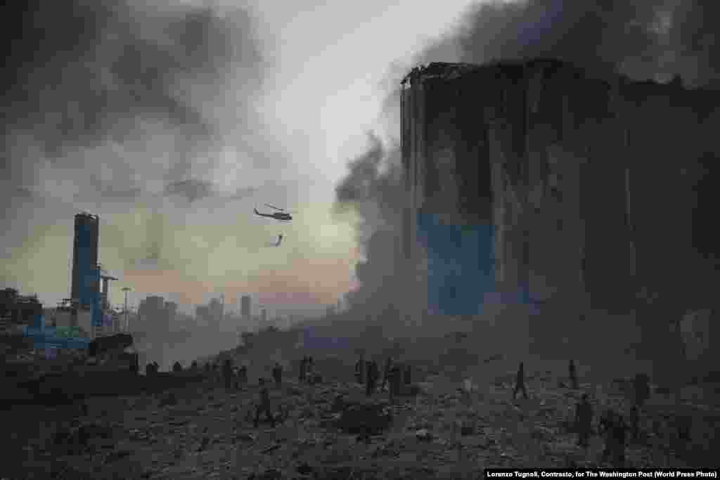 Здымак з фотарэпартажу «Выбух у порце Бэйрута». На месцы катастрофы працуюць пажарныя (4 жніўня 2020). Каля дзесяці пажарных загінулі на месцы выбуху. Першае месца ў катэгорыі «Тэрміновыя навіны, фотарэпартаж», аўтар – Лёрэнса Тугнолі