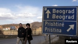 Kosovo -- A couple walks past a traffic sign in the ethnically divided town of Mitrovica, 20Mar2013