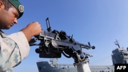 An Iranian Army soldier stands guard on a military speed boat during navy exercises in the Strait of Hormuz.