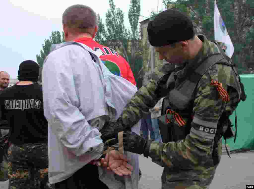 A man accused of looting is taken into custody by a volunteer member of the Vostok Battalion.