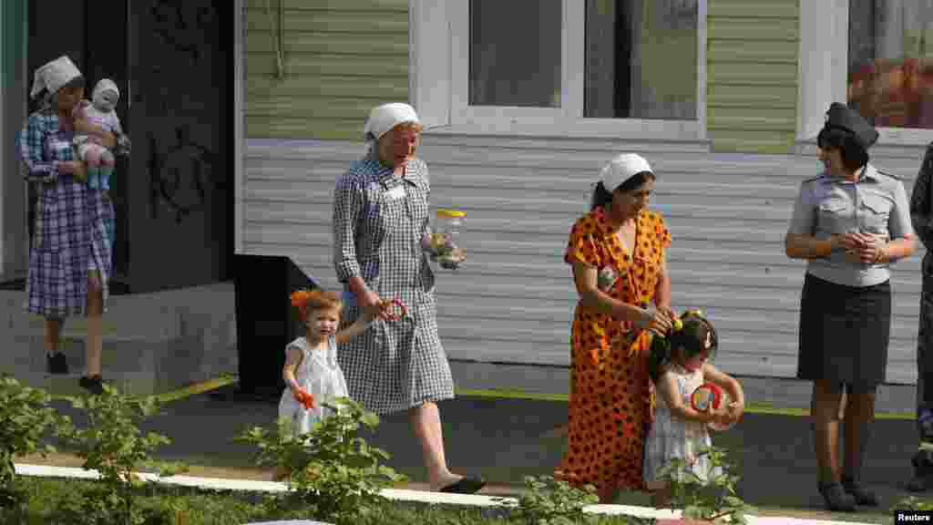 Inmates walk with their children as a guard watches in the courtyard of a "children's home," located inside a female prison camp in the Siberian city of Krasnoyarsk.