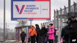 Ljudi čekaju autobus na autobuskoj stanici pored bilborda koji promoviše predstojeće predsjedničke izbore, u Sankt Peterburgu, Rusija, 20. decembra , 2023.