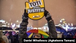 A Romanian man holds aloft a sign reading "All for justice" during a demonstration against planned changes in the law.