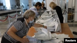 Izborni radnici prazne glasačku kutiju na biračkom mjestu nakon takozvanog referenduma o pridruživanju regija Ukrajine pod ruskom kontrolom Rusiji, u Sevastopolju, Krim, 27. septembar 2022.