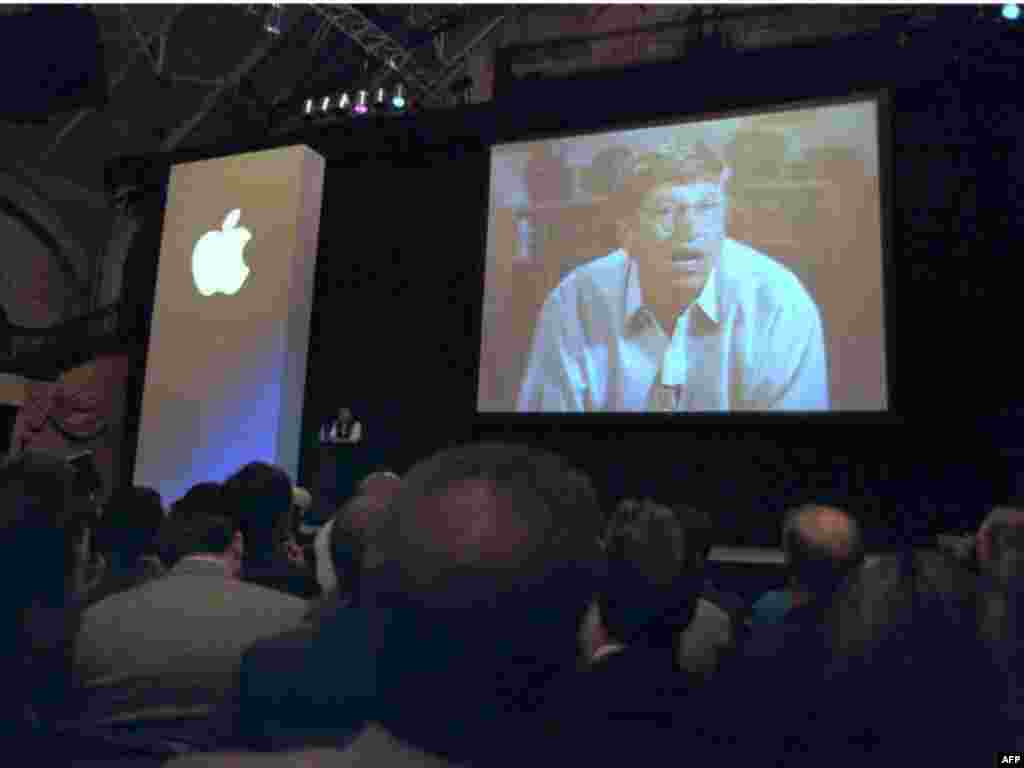 Microsoft Chairman Bill Gates appears on screen next to Apple CEO Jobs (center, on stage) to announce a partnership in August 1997 that included shareholding and Gates' seat on the Apple board.
