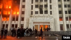 Protesters are seen on January 5 outside the Almaty mayor’s office, which was set ablaze during the protests.