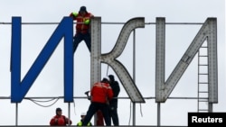 Workers dismantle an "Alexander the Great" sign from the airport in Skopje on February 24.