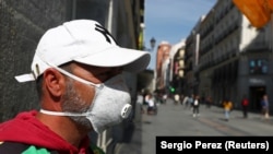 Un vânzător de bilete la loterie așteaptă cumpărători pe o stradă centrală din Madrid, altă dată foarte animată