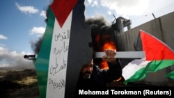 WEST BANK -- A demonstrator carries a model of a map with the colors of the Palestinian flag reading "Jerusalem is the eternal capital of Palestine" during a protest against the U.S. President Donald Trump's Middle East peace plan, in the village of Bili