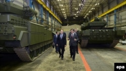 Președintele rus Vladimir Putin (stânga) îl ascultă pe Andrei Terlikov, șeful Biroului de proiectare a construcțiilor de mașini de transport Ural, în timp ce trec pe lângă vehicule militare la fabrica Uralvagonzavod din Nijni Tagi, Rusia. (foto de arhivă)