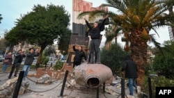 Oamenii s-au urcat pe statuia doborâtă a fostului președinte sirian, Hafez al-Assad. Damasc, 8 Decembrie. 