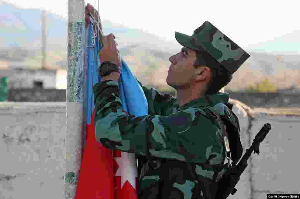 An Azerbaijani soldier hoists his country's flag during a ceremony in the village of Mincivan, which was recently taken from Armenian forces. 