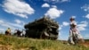 A woman walks past a rocket launcher during the International Military-Technical Forum ARMY-2015 in the Russian military Patriot park in Kubinka, outside Moscow.