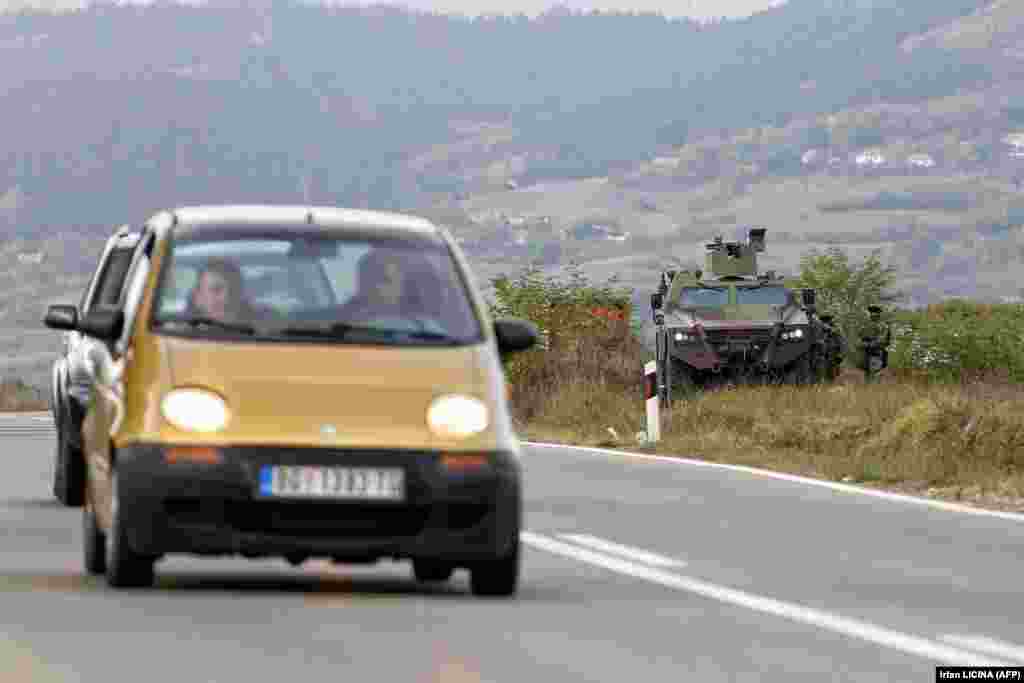 Vozila koja se kreću putem, u blizini oklopnog vozila Vojske Srbije, u Rudnici. (27. septembar) 