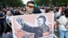 Un protestatar ține o pancardă cu imaginea prim-ministrului Ungariei, Viktor Orban, ilustrat ca un lider comunist din China, 5 iunie 2021.
