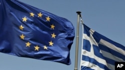 The European Union and Greek flags fly above the Parthenon in Athens.