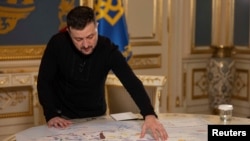Președintele Ucrainei, Volodimir Zelenski, le arată jurnaliștilor agenției Reuters o hartă cu depozitele de minereuri rare pe care vrea să le împartă cu Statele Unite. 