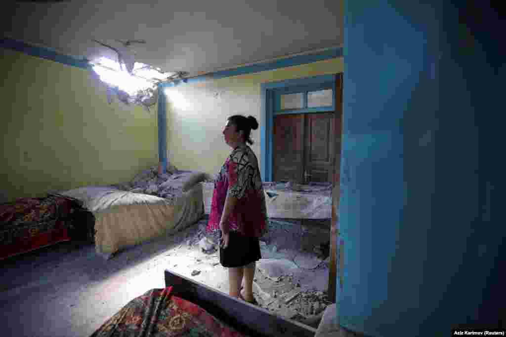 A woman in the Azerbaijani village of Dondar Gushchu inspects damage to her home caused by an Armenian shell.