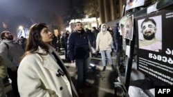 O femeie din Tbilisi se uită la un afiș care arată oameni bătuți de poliția georgiană. 9 decembrie.